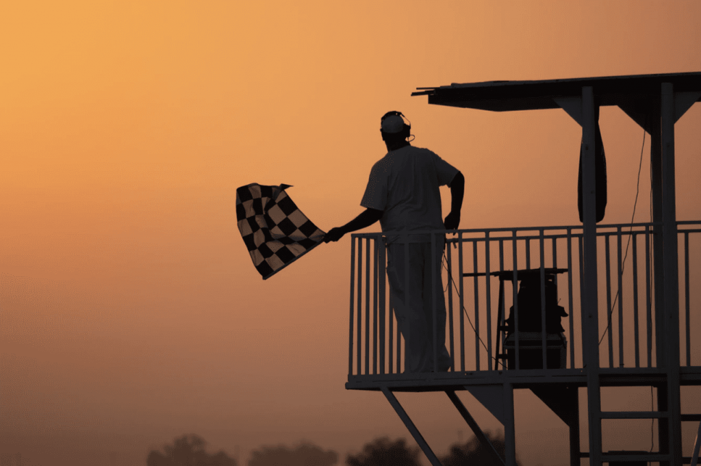 man waving flag in evening at a race