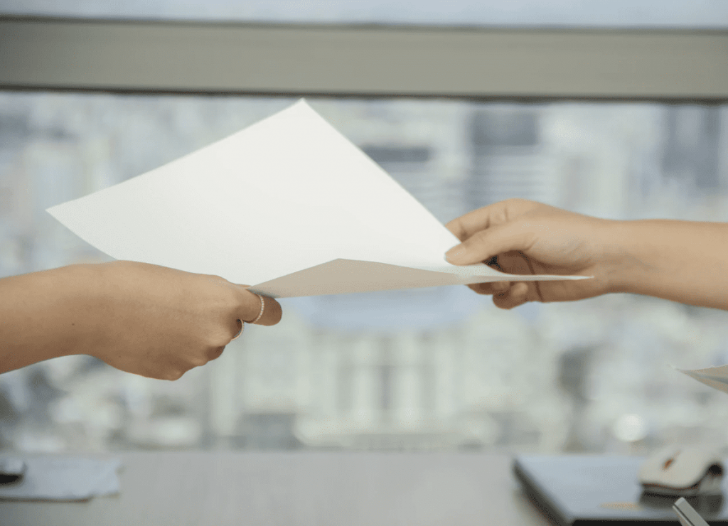 person handing someone else a slip of paper to do with freelance work