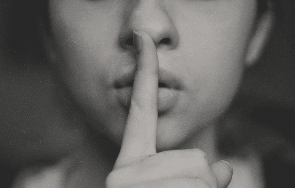 woman with finger over her lips to demonstrate being quiet