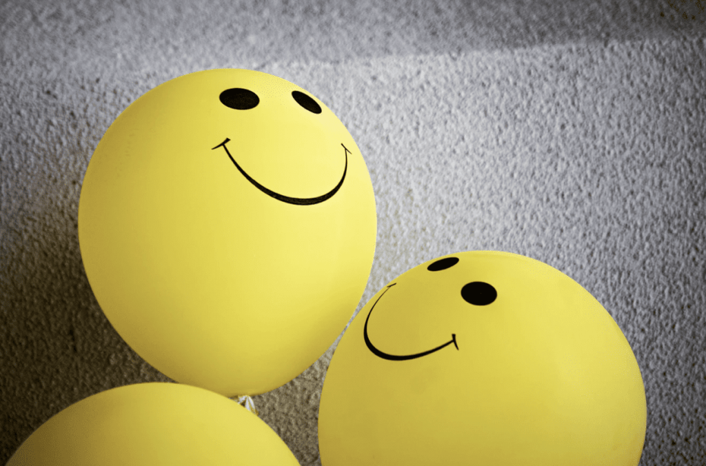 2 yellow balloons with smiley faces painted onto them