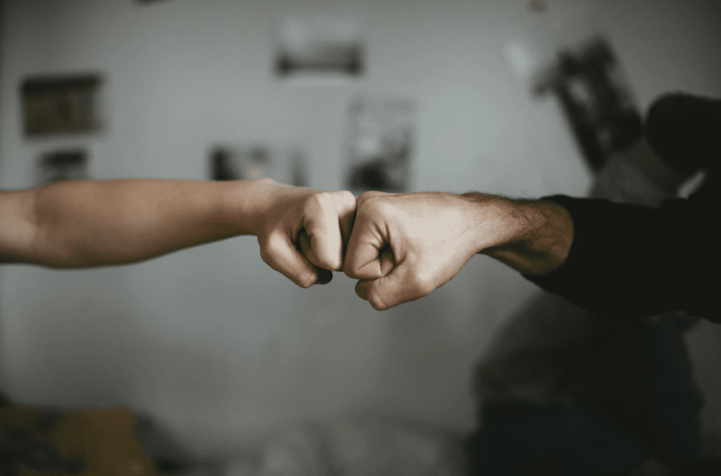 two people putting their fists together to signal unity and friendship