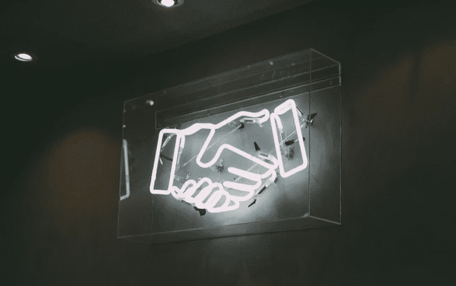 neon light displaying shaking hands