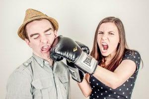 Woman with boxing gloves punching a man in a hat. This article explains why hiring your friends for freelance work can often be a bad idea.