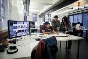Image of three people working together in a modern agency. Choosing to work with an agency can have a big impact on ROI.