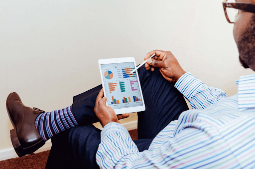 man in suit sitting cross legged looking at iPad with motion graphics on the screen