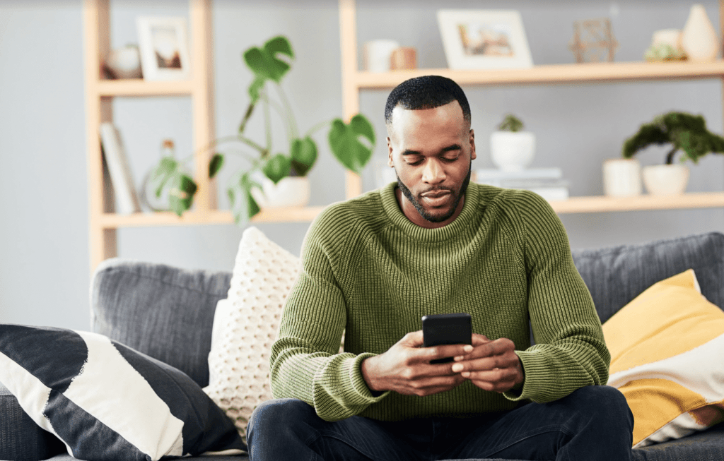 man looking down at phone in living room setting