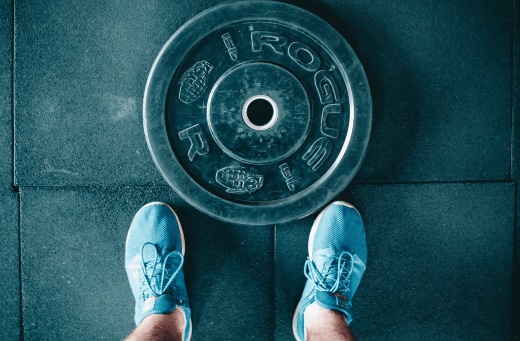 man standing behind weight to symbolise not appreciating weaknesses in a 5-year business plan